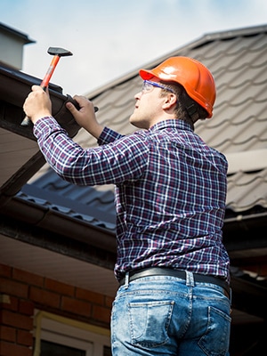 Roofer Inspecting Gutter System